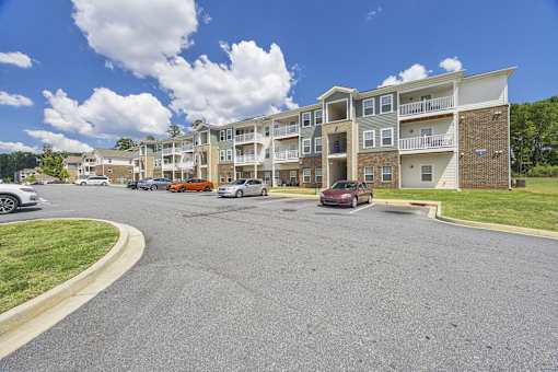 A parking lot in front of a multi-story apartment building.