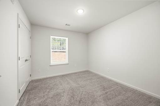A room with a carpeted floor and a window.