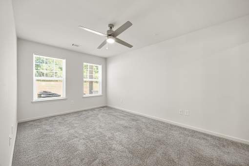 A room with a ceiling fan and car pictures on the wall.