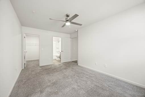 A room with a ceiling fan and carpeted floor.