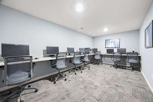 A conference room with a carpeted floor and grey chairs.