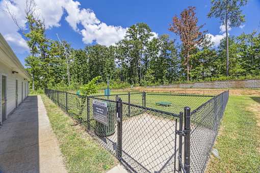 A fenced area with a sign and a tree in the background.