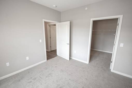 A room with two open doors and a carpeted floor.
