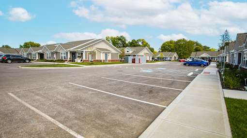 A parking lot with a few cars and a building in the background.