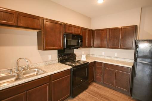 A kitchen with dark wood cabinets and black appliances.