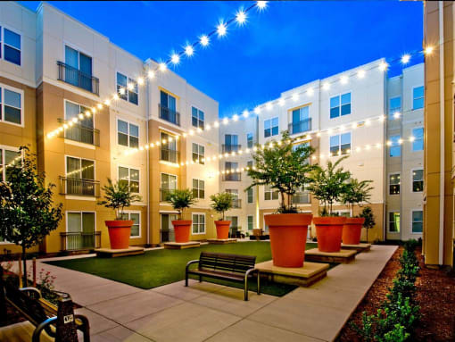 a courtyard with benches and potted plants in front of an apartment building