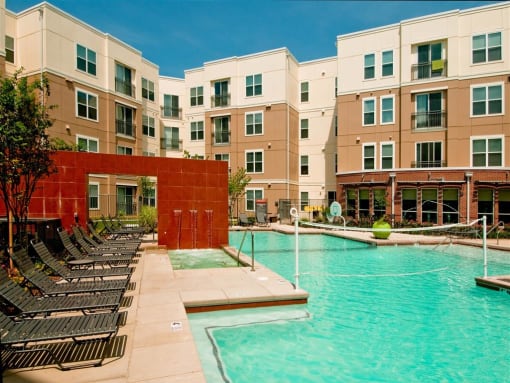 a swimming pool with chaise lounge chairs and a building in the background