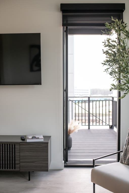 a living room with a door to a balcony and a television