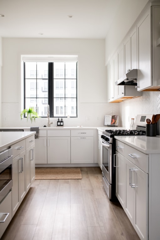 a kitchen with white cabinets and a window