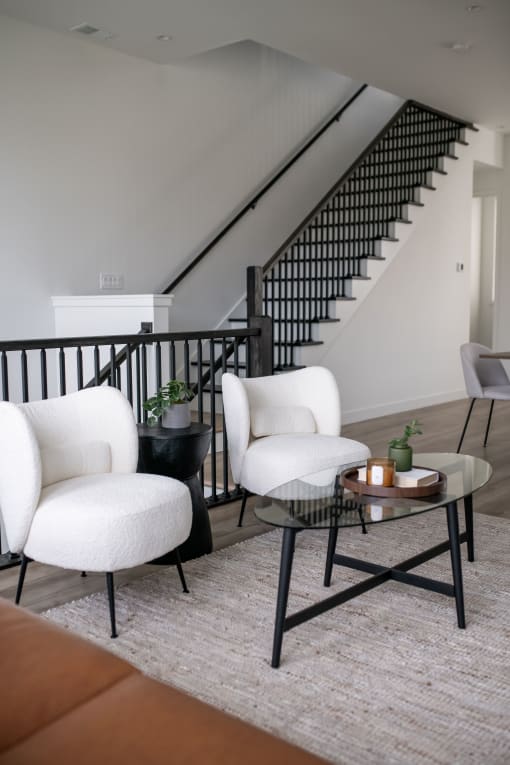 a living room with two white chairs and a coffee table