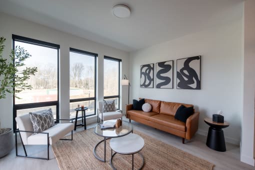a living room with a brown leather couch and two chairs and a large window