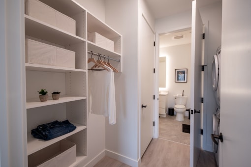 a walk in closet with open shelving and a bathroom with a toilet