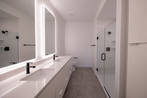 a white bathroom with two sinks and a shower