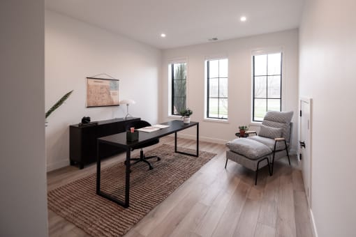 a living room with a desk and a chair and a rug