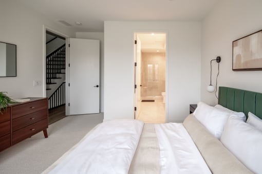 the master bedroom has a large bed with white sheets and a green couch