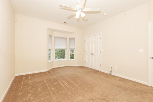 a empty living room with a ceiling fan and a window