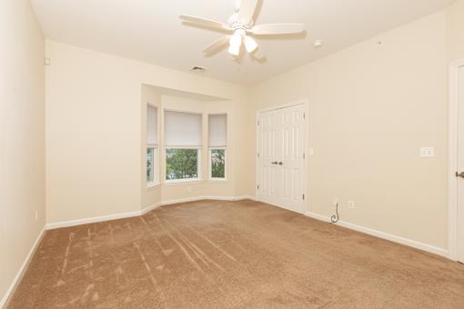 an empty living room with a ceiling fan and a window