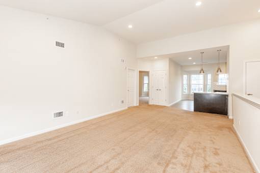 an empty living room and kitchen with white walls and wood floors