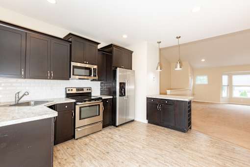 a large kitchen with black cabinets and stainless steel appliances