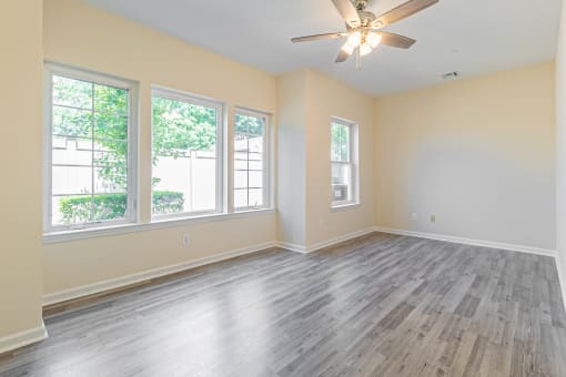 an empty living room with wood floors and a ceiling fan