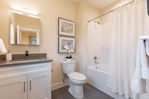 A white bathroom with a toilet, sink, and shower.