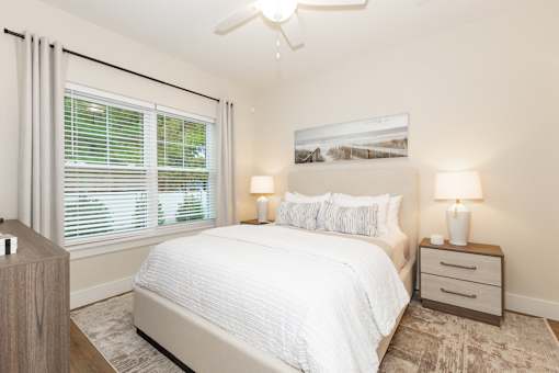 A bedroom with a large bed, two lamps, and a ceiling fan.