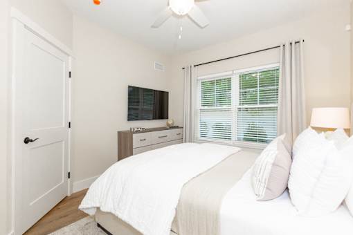 A bedroom with a bed, a dresser, and a ceiling fan.