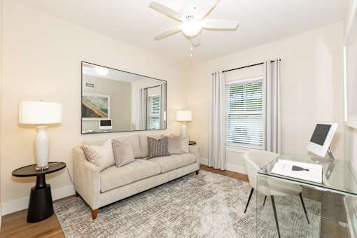 A living room with a couch, a table, a chair, and a mirror.