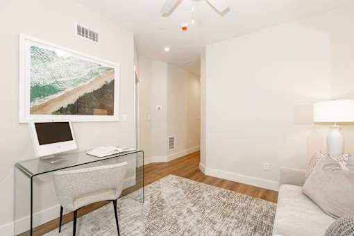 A room with a glass desk and a painting on the wall.