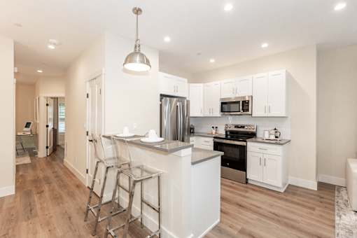 A modern kitchen with white cabinets and a wooden floor.