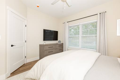A bedroom with a bed, dresser, and window.
