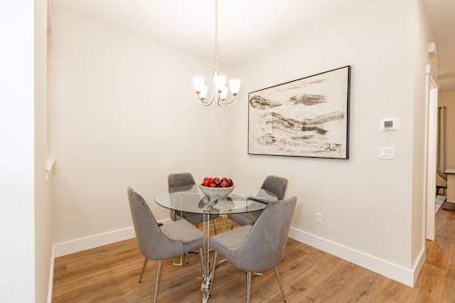 A dining table with four chairs and a bowl of strawberries on it.