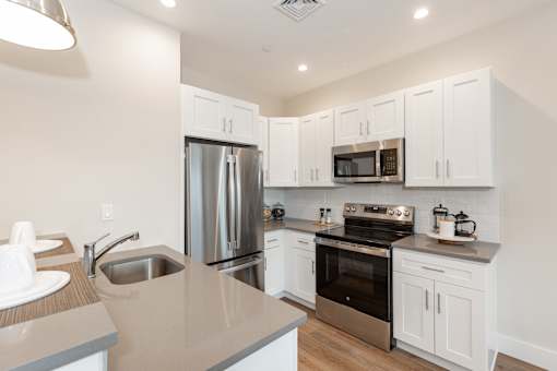 A modern kitchen with white cabinets and stainless steel appliances.