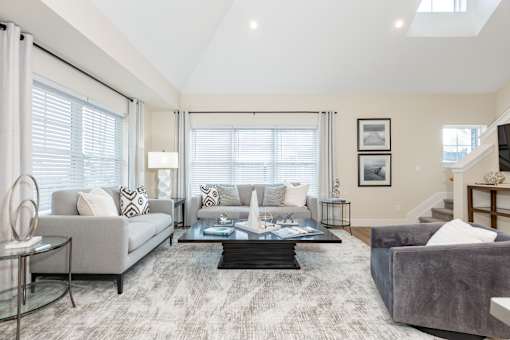 A living room with a grey couch, a glass coffee table, and a grey sofa.