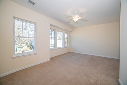 a bedroom with a ceiling fan and three windows