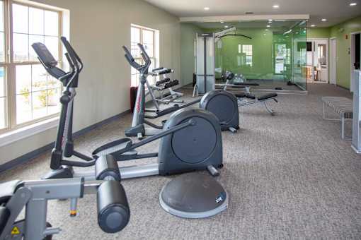 A gym with a variety of exercise equipment including treadmills, stationary bikes, and weight machines at Evergreen, Merrillville, 46410