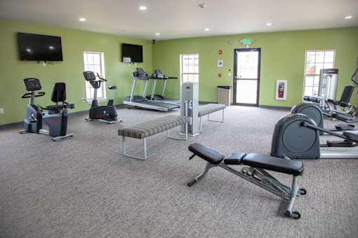 A gym with a variety of equipment including treadmills, exercise bikes, and weight machines at Evergreen, Merrillville, 46410