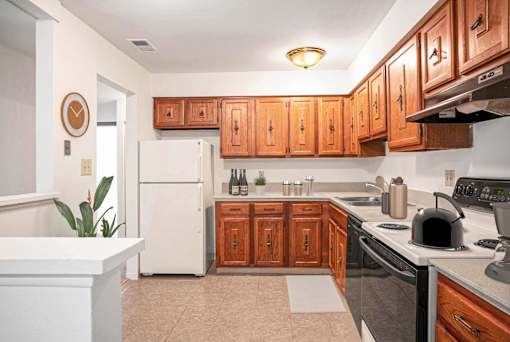 A kitchen with wooden cabinets and a white refrigerator at Hampton in Highland Apartments, Indiana, 46322