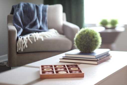 A small green plant sits on top of a stack of books next to a small wooden box with compartments.at Vita on Grant, Indiana, 46410