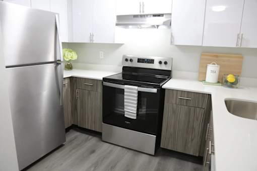 A modern kitchen with a stainless steel refrigerator and a stove top oven.at Vita on Grant, Merrillville, IN 46410
