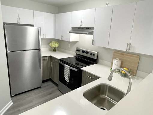 A modern kitchen with a stainless steel refrigerator and a stove top oven.at Vita on Grant, Indiana, 46410