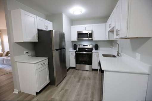 A kitchen with white cabinets and stainless steel appliances. at Evergreen, Merrillville
