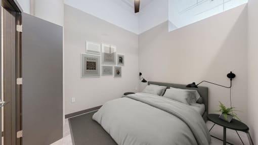 a bedroom with white walls and a bed with a grey comforter