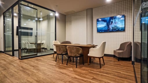 a conference room with a table and chairs and a tv on the wall