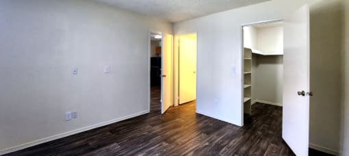a bedroom with wood laminate floors, white walls and a walk in closet