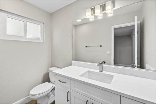 A white bathroom with a toilet, sink, and mirror.