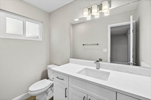 A white bathroom with a toilet, sink, and mirror.