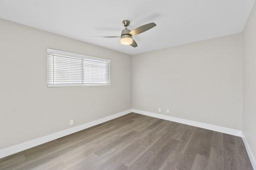 A room with a ceiling fan and a window with blinds.