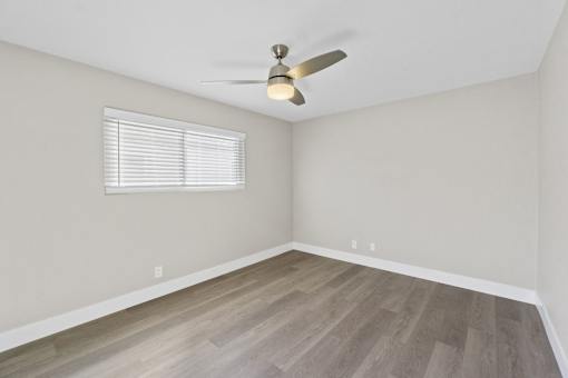 A room with a ceiling fan and a window with blinds.