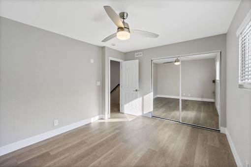 A room with a ceiling fan and a sliding glass door leading to a balcony.